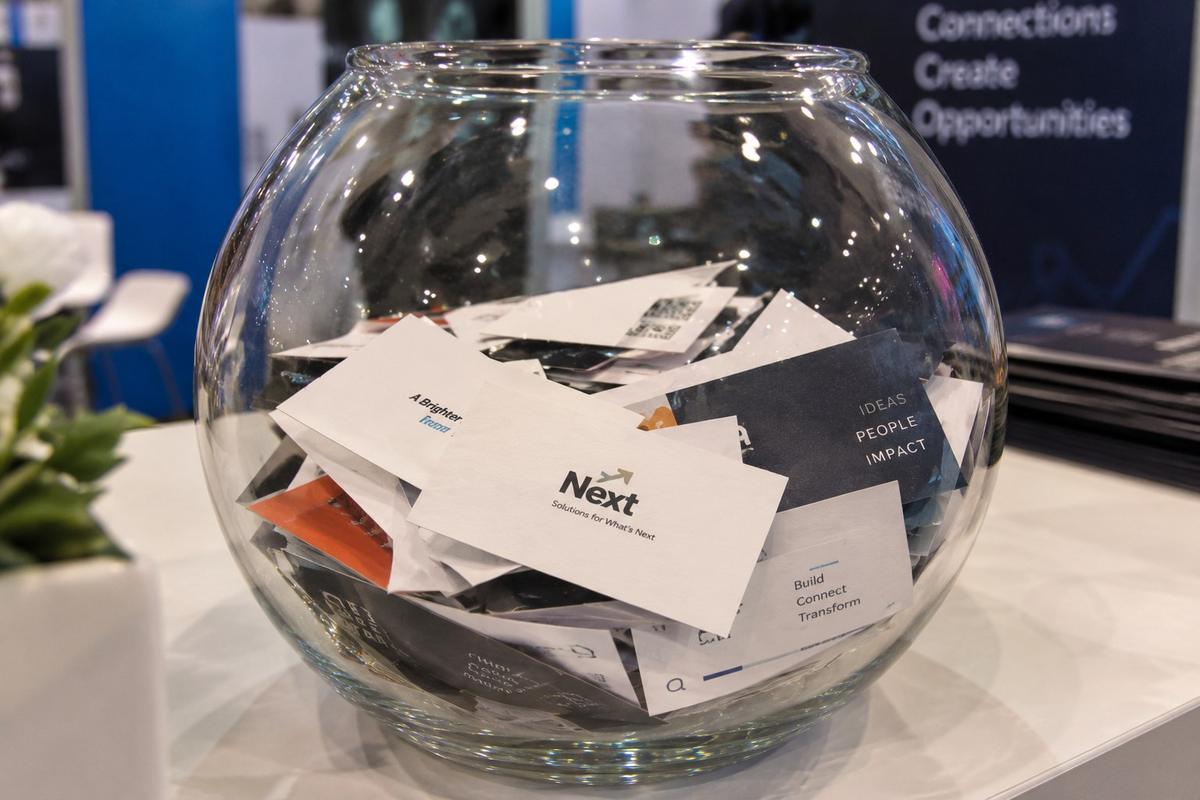 A glass bowl of visiting cards collected on an exhibition stall counter