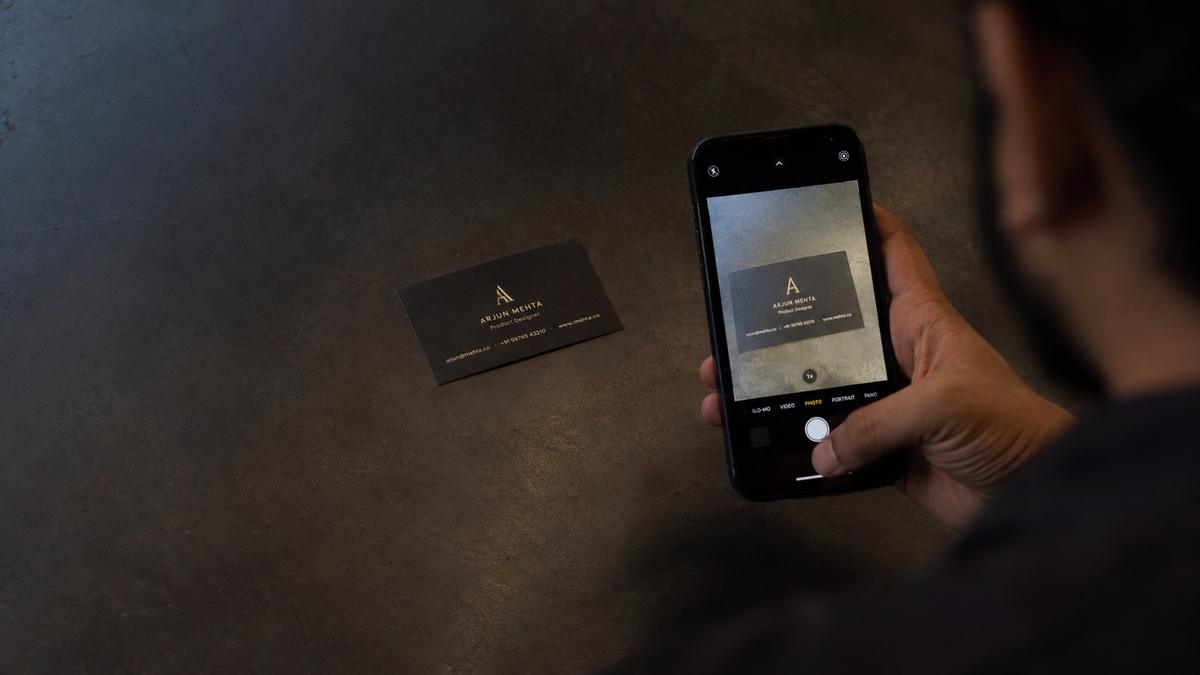 A visiting card being photographed on a phone at an exhibition stall